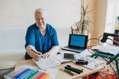 Yaşlılar için hobi fikirleri. Emeklilik hobileri, yaşlılar için hobiler. Kısıtlı Hareketli Yaşlılar için etkinlikler. Olgun, yaşlı, kıdemli kadın sanatçı el yazısı ve el yazısı çalışıyor..