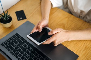 Kara Cuma, online satış. İnternet Satın Alma, Çevrimiçi Alışveriş, E-ticaret web sitesi, tablet veya cep telefonu. Evde elinde kredi kartı olan ve dizüstü bilgisayar kullanan genç bir kadın.