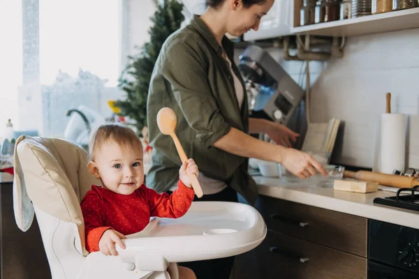 Cozy Christmas at home. Family preparation holiday dessert. Mother and baby toddler daughter play together and cooking gingerbread on kitchen — Stock Photo, Image