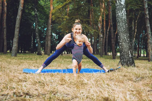 Mami y yo Yoga para bebés y mamás posparto. Zen Family Yoga. Madre posparto e hija niña que tiene clases de yoga al aire libre en el fondo de la naturaleza —  Fotos de Stock