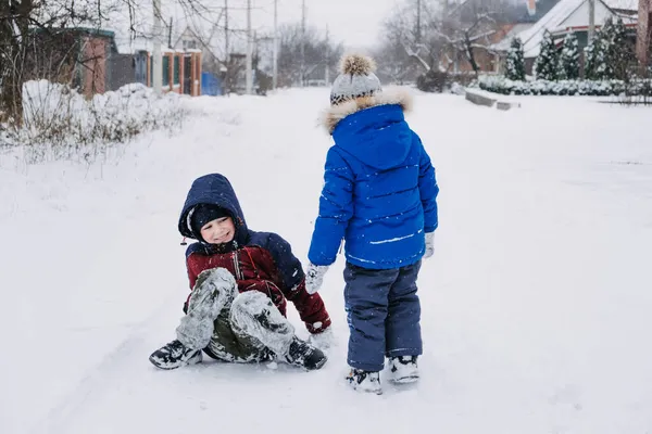 Zimowe zajęcia na świeżym powietrzu dla dzieci. Dzieci bawią się na przedmieściach, zbierają się na zimowym podwórku. Chłopcy bawią się ze śniegiem. Skupienie selektywne — Zdjęcie stockowe