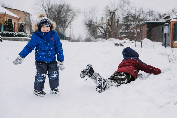 Zimowe zajęcia na świeżym powietrzu dla dzieci. Dzieci bawią się na przedmieściach, zbierają się na zimowym podwórku. Chłopcy bawią się ze śniegiem. Skupienie selektywne — Zdjęcie stockowe
