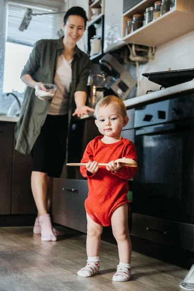 Glückliche Mutter und kleines Baby-Kleinkind-Mädchen backen Weihnachtsplätzchen in der heimischen Küche. Mutter und kleines Mädchen backen Weihnachts-Lebkuchen für das Familienessen an Heiligabend. — Stockfoto