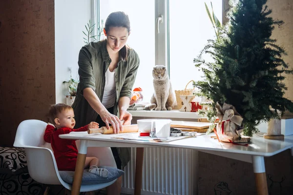 Happy mother and little baby toddler girl making christmas cookies in home kitchen. Mother and little girl baking Christmas gingerbread pastry for family dinner on Xmas eve. — Stock Photo, Image