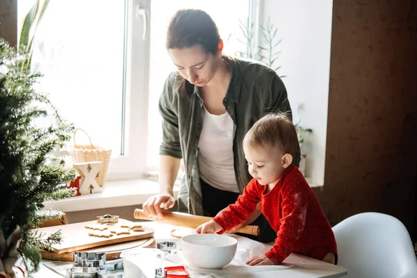 Happy mother and little baby toddler girl making christmas cookies in home kitchen. Mother and little girl baking Christmas gingerbread pastry for family dinner on Xmas eve. — Stock Photo, Image