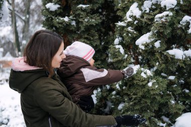 Bebekle En İyi Açık Hava Kış Faaliyetleri. Kışın yeni yürümeye başlayan bebek, Soğuk Hava 'da çocukları nasıl koruyacağını. Anne ve küçük kızı kış parkında yürüyor.