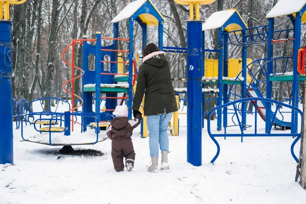 Najlepsze zajęcia zimowe na świeżym powietrzu z dzieckiem. Dziecko maluch w zimie, Jak chronić dzieci w zimnej pogodzie. Matka i córeczka spacerują po zimowym parku — Zdjęcie stockowe