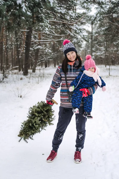 Rodzinne zajęcia na świeżym powietrzu dla szczęśliwych świąt Bożego Narodzenia. Szczęśliwy ojciec i matka bawiący się z małą córeczką maluszka w zimowym parku, las. Szczęśliwa rodzina dostaje choinkę — Zdjęcie stockowe