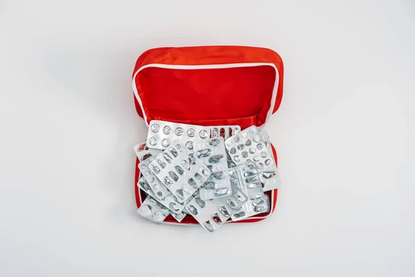 Side effects of pills and medication. Many used empty pills pack and medications blisters in red first aid kit on white background