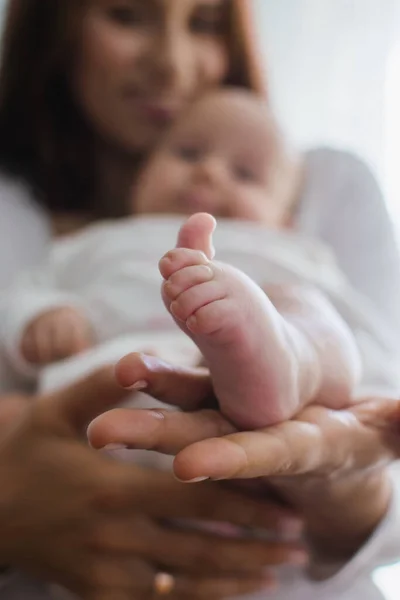 Seguro de salud para bebés recién nacidos. Seguro de vida para bebé nuevo. Madre sosteniendo en las manos los pies del bebé recién nacido. Bebé pies en las manos de los padres — Foto de Stock