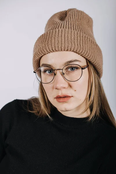 Retrato emocional sincero inalterado de jovem mulher feliz com cabelos longos loiros em fundo cinza. Estúdio tiro de moda casual hipster menina em malha chapéu gorro. — Fotografia de Stock