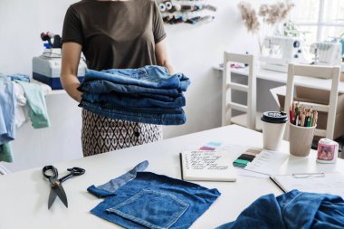 Tekrar kullan, onar, güncelle. Sürdürülebilir moda, dairesel ekonomi. Denim yükseltme fikirleri, tamir ve eski kot pantolon. Dikiş atölyesindeki eski kot pantolon kumaş yığınının yakın çekimi.