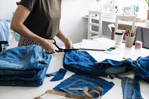 Tekrar kullan, onar, güncelle. Sürdürülebilir moda, dairesel ekonomi. Denim yükseltme fikirleri, tamir ve eski kot pantolon. Dikiş atölyesindeki eski kot pantolon kumaş yığınının yakın çekimi.