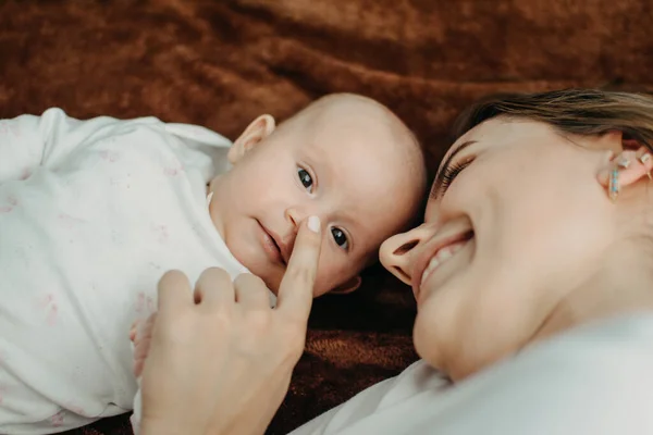 Ropa de bebé recién nacido de algodón orgánico. Lindo bebé recién nacido en traje de cuerpo blanco hecho de algodón orgánico acostado en la cama. Tonos naturales, ropa de bebé unisex — Foto de Stock