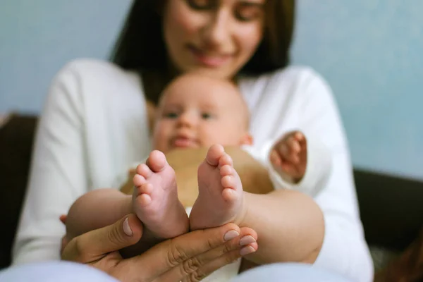 Cuidado de la piel del bebé recién nacido. Primer plano de los pies del bebé en manos de la madre. Pies de bebé recién nacido. Familia feliz y paternidad — Foto de Stock