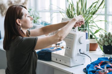 Sürdürülebilir moda, Denim Upcycle Fikirleri, Eski Kotları Kullanmak, Kotları Yenilemek, Eski Kotları Yeniden Kullanmak, Upcycle Stuff. Kadın terzi dikiş atölyesinde eski kot pantolonları kesip onarıyor.