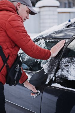 Frozen car door. Automobile car door or lock is frozen shut. Man driver trying to open frozen car door or lock