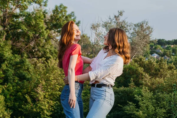 Dos felices alegres jóvenes amigas amorosas divirtiéndose en el fondo de la naturaleza. Dos amigos Gen z Millennials bailando y jugando en el prado —  Fotos de Stock