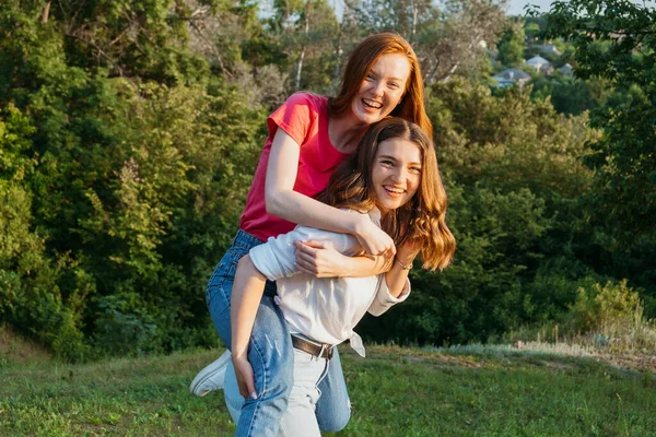 Twee vrolijke jonge liefdevolle vriendinnen die plezier hebben op de natuur achtergrond. Twee vrienden Gen z Millennials dansen en spelen in weide — Stockfoto