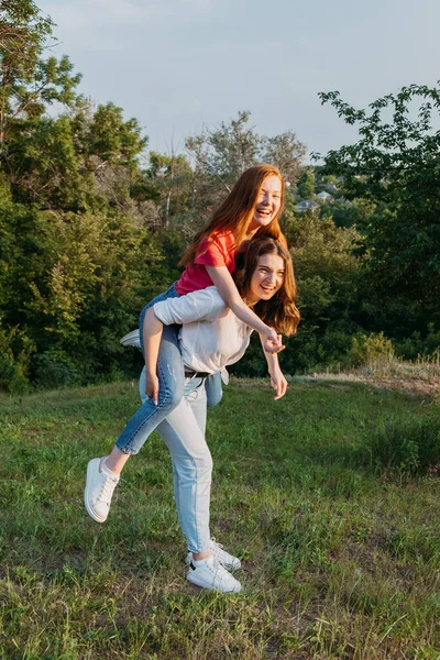 两个快乐快乐的、年轻的、有爱心的女朋友，在大自然的背景下玩得开心。两个朋友Gen z Millennials在草地上跳舞和玩耍 — 图库照片