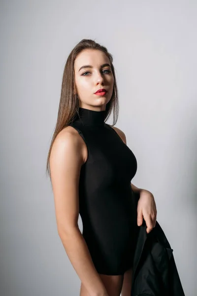 Retrato de estúdio de mulher jovem com cabelo longo. Menina elegante na moda em bodysuit preto no fundo cinza — Fotografia de Stock
