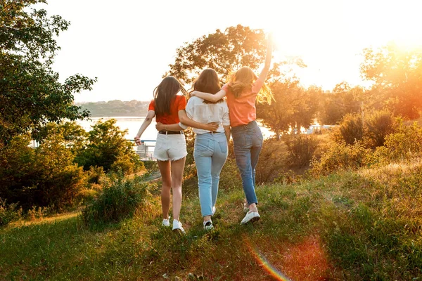 夏令营、暑期班、友人大学。三个快乐的女孩朋友在夏日落日的背景下跳舞和跳跃。暑假之友小组 — 图库照片