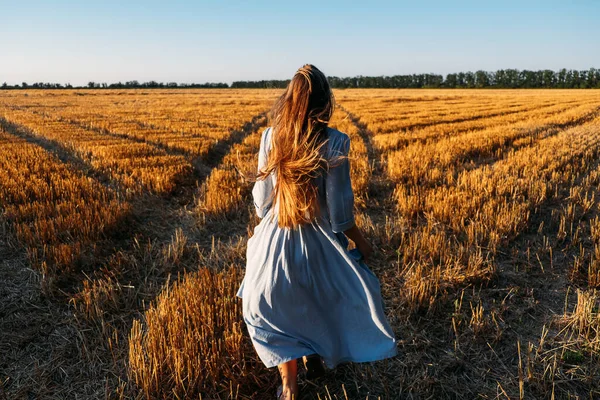 Mavi keten elbiseli kadın günbatımı tarlasında doğanın tadını çıkarıyor. Stres ve psikolojik dayanıklılık. Stres ve Kaygıları Azaltmak İçin Doğada Zaman Geçirin.