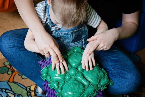 Sinnesspiele für Kinder mit besonderen Bedürfnissen. Hilfe und Aktivitäten für Kinder mit Behinderungen, Zerebralparese. Junge mit Zerebralparese spielt mit Sinnesmatten-Massage-Spiel Puzzlematten für Kinder — Stockfoto