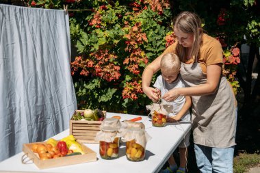 Sebzeleri nasıl uzun süre saklayıp muhafaza edeceğimizi. Sebzeleri Bahçeden Konserve ve Koruyun. Mutlu aile anne ve çocuğu yaz günü bahçede sebze konservesi yapıyorlar.