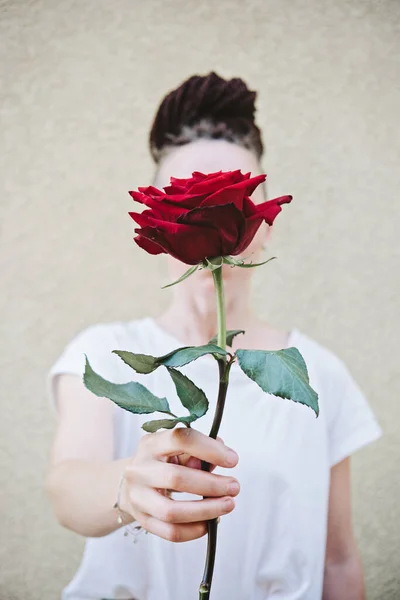 Retrato sin rostro de una mujer sosteniendo rosa roja en la mano. Primer plano de las manos femeninas sosteniendo a Rose. Hipster mano mujer sosteniendo una rosa roja — Foto de Stock