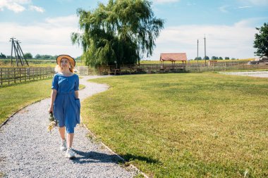 Summer Village 'daki yazlıklar, Tatil Kiralama. Yurtiçi Seyahat, Yerel Seyahat, Yaz Ülke Seyahati. Kır kaçamakları. Hasır şapkalı genç kadın çiftlikte yaz tatilinin tadını çıkarıyor.