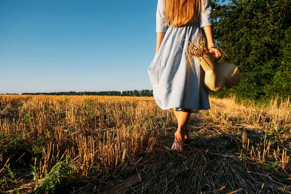 Connect with nature, Slow Down, Be Present, Get Into Your Senses. Barefoot woman in linen blue dress walks through sloping wheat field. — Stock Photo, Image