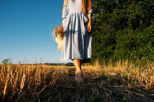 Verbind je met de natuur, vertraag, wees aanwezig, ga naar je zintuigen. Barefoot vrouw in linnen blauwe jurk loopt door hellend tarweveld. — Stockfoto