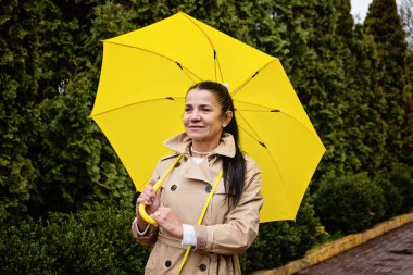 Kıdemli Akıl Sağlığı, Bilişsellik ve Duyguyu Geliştirme. Yetişkinlerin akıl sağlığı. Sarı yağmurluklu mutlu beyefendi kadın hayatın tadını çıkarıyor ve parkta yürüyor.
