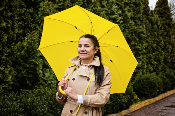 Kıdemli Akıl Sağlığı, Bilişsellik ve Duyguyu Geliştirme. Yetişkinlerin akıl sağlığı. Sarı yağmurluklu mutlu beyefendi kadın hayatın tadını çıkarıyor ve parkta yürüyor.