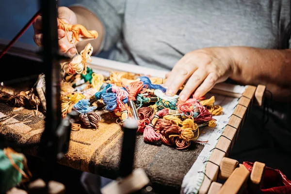 Senior elderly female hands embroider choose cotton craft threads. Handmade cross stitch embroidery in women s hands. Cross stich set in process — Fotografia de Stock