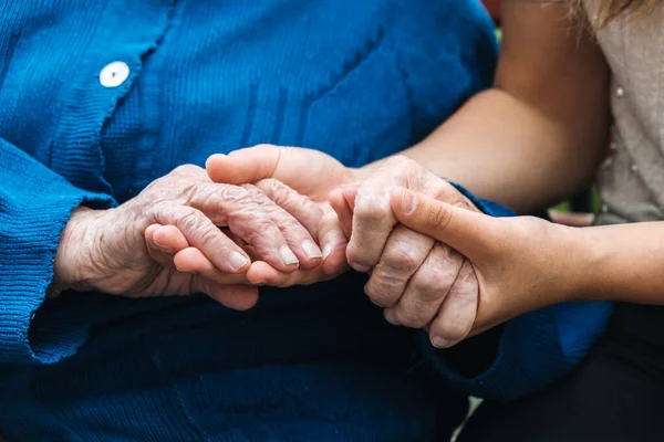 Благодійність для літніх людей. Молоді руки тримають старі літні руки. Підтримка концепції літніх людей . — стокове фото