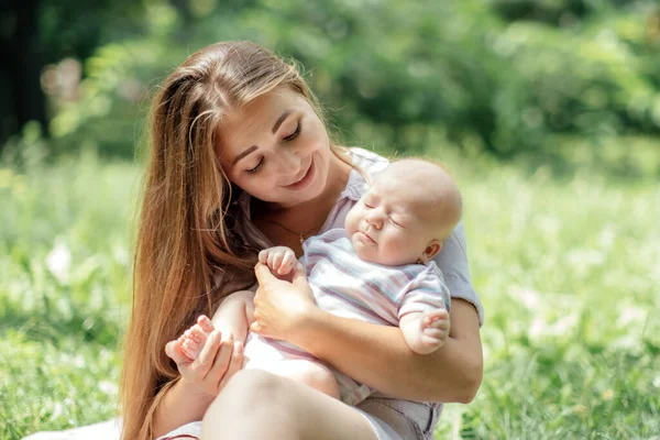 Bebé recién nacido pasando tiempo fuera. Madre feliz y sonriente con su bebé recién nacido pasando tiempo en el parque. Recibir aire fresco y luz solar natural para bebés. — Foto de Stock
