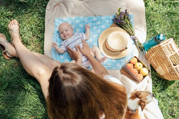 Newborn baby spending time outside. Happy and smiling mother with her newborn baby spending time in the park. Getting fresh air and natural sunlight for babies