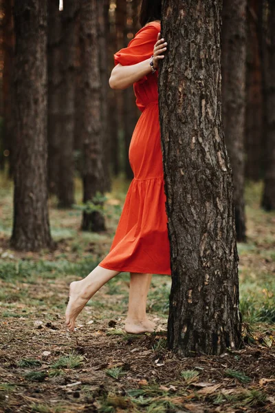 Woman with fern tattoo hugging trees and enjoying nature in the pine forest. Benefits of Tree Hugging For Mental Health.