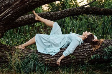 Doğa ve akıl sağlığı. Doğa ve Akıl Sağlığını Geliştirme ile bağlantı kurun. Çıplak ayaklı kadın doğada ağaçların yanında dinleniyor.