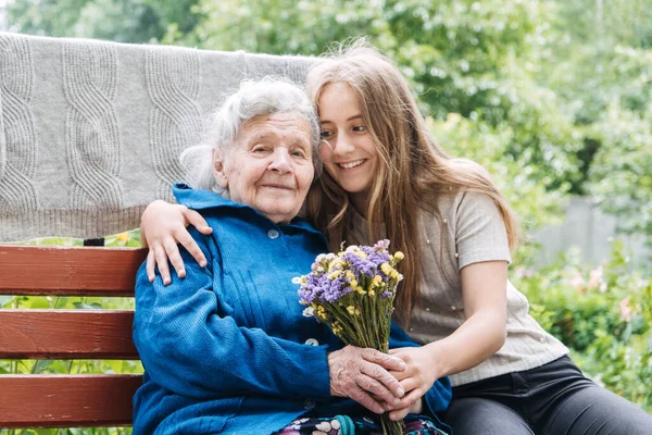 Holiday Gift Donations for Senior Citizens. Gift to help struggling seniors. Volunteer girl and Senior elderly woman with gift, flowers bouquet and basket of groceries