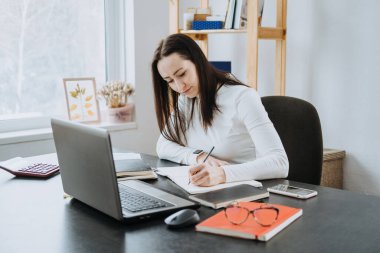 Muhasebeciler için Temel Muhasebe Formülleri. Hesap makinesi ve dizüstü bilgisayarla çalışan kadın muhasebeci.