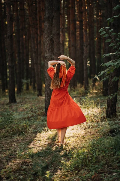 Midsummer solstice ritual. Celebrating summer solstice. Significance of the solstice in Paganism. Alone Woman in red dress dance on sun pine forest nature background