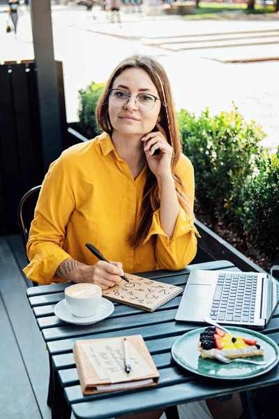 Mujer Freelancer Escribiendo Números Bloc Notas Mientras Trabaja Con Portátil — Foto de Stock