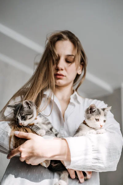 Cat Adoption, Adopt kitten from rescues and shelters. Portrait of woman playing with two outbred homeless adopted grey kittens in bed at home