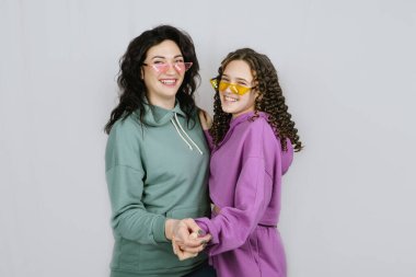 Renkli gözlüklü mutlu anne ve genç kızın stüdyo portresi. Birlikte eğlenip oynaşıyorlar. Annesiyle arkadaş olan ergen bir kız.