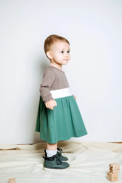 Baby fashion. Unisex color clothes for babies. Cute baby girls in neutral color palette cotton dress on light background.