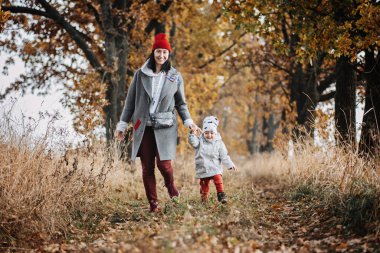 Family Fall Activities. Happy family mom and toddler baby girl playing outdoors in fall park. Little girl and her mother in the autumn park.