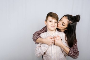 Ergen çocuklar yetiştirmek, ergen yetiştirmek. Mutlu genç çocuğun beyaz arka planda annesine sarılışının stüdyo resmi. Mutlu aile, anne ve oğul